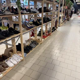 Houten stellingen met verschillende tweedehands schoenen en kleding in een kringloopwinkel