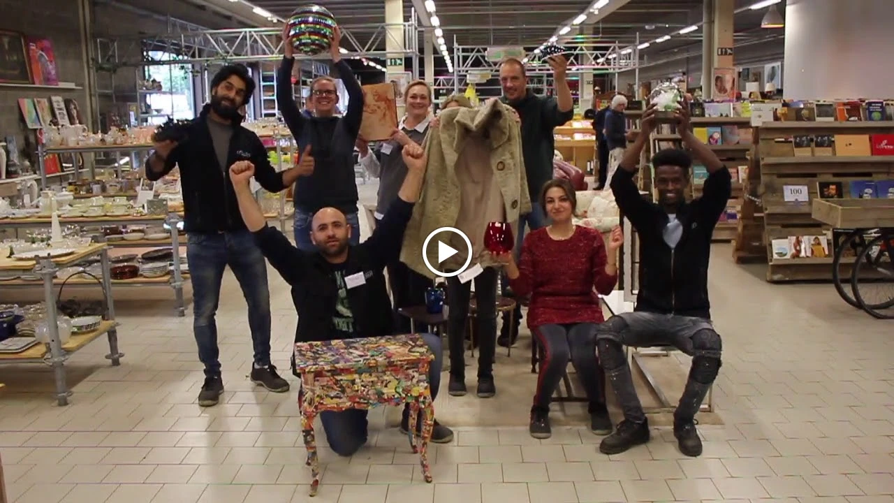 Groep medewerkers en vrijwilligers poseren samen in de winkel met enthousiaste poses