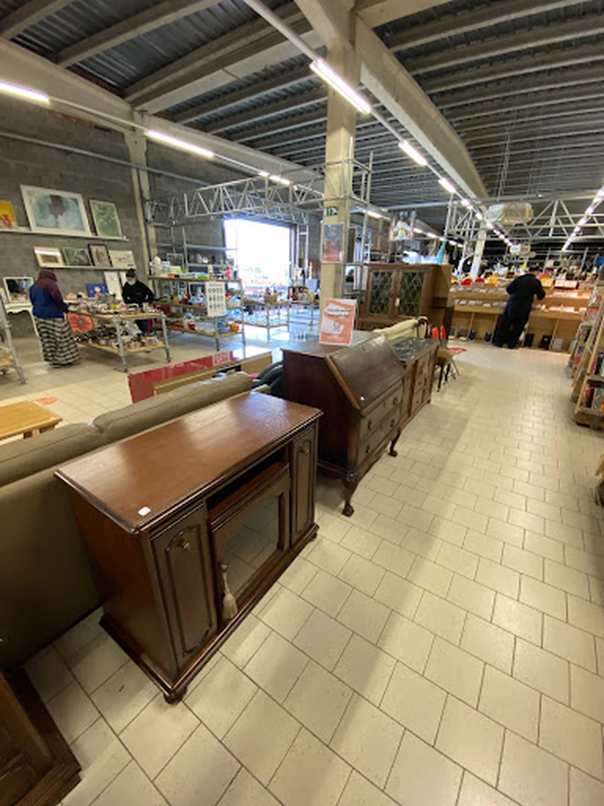 Winkelvloer met meubelstukken en stellingen vol spullen in een kringloopwinkel