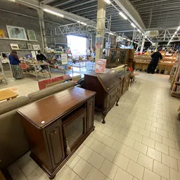 Winkelvloer met meubelstukken en stellingen vol spullen in een kringloopwinkel
