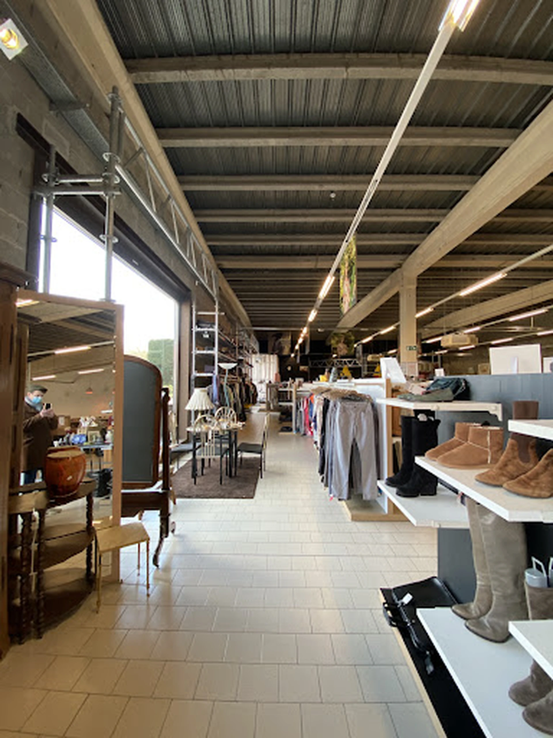 Winkelhal met stellingen vol kleding, schoenen en huishoudspullen langs het gangpad