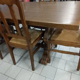 Houten eettafel met vier stoelen, gemaakt van donker hout met rieten zittingen
