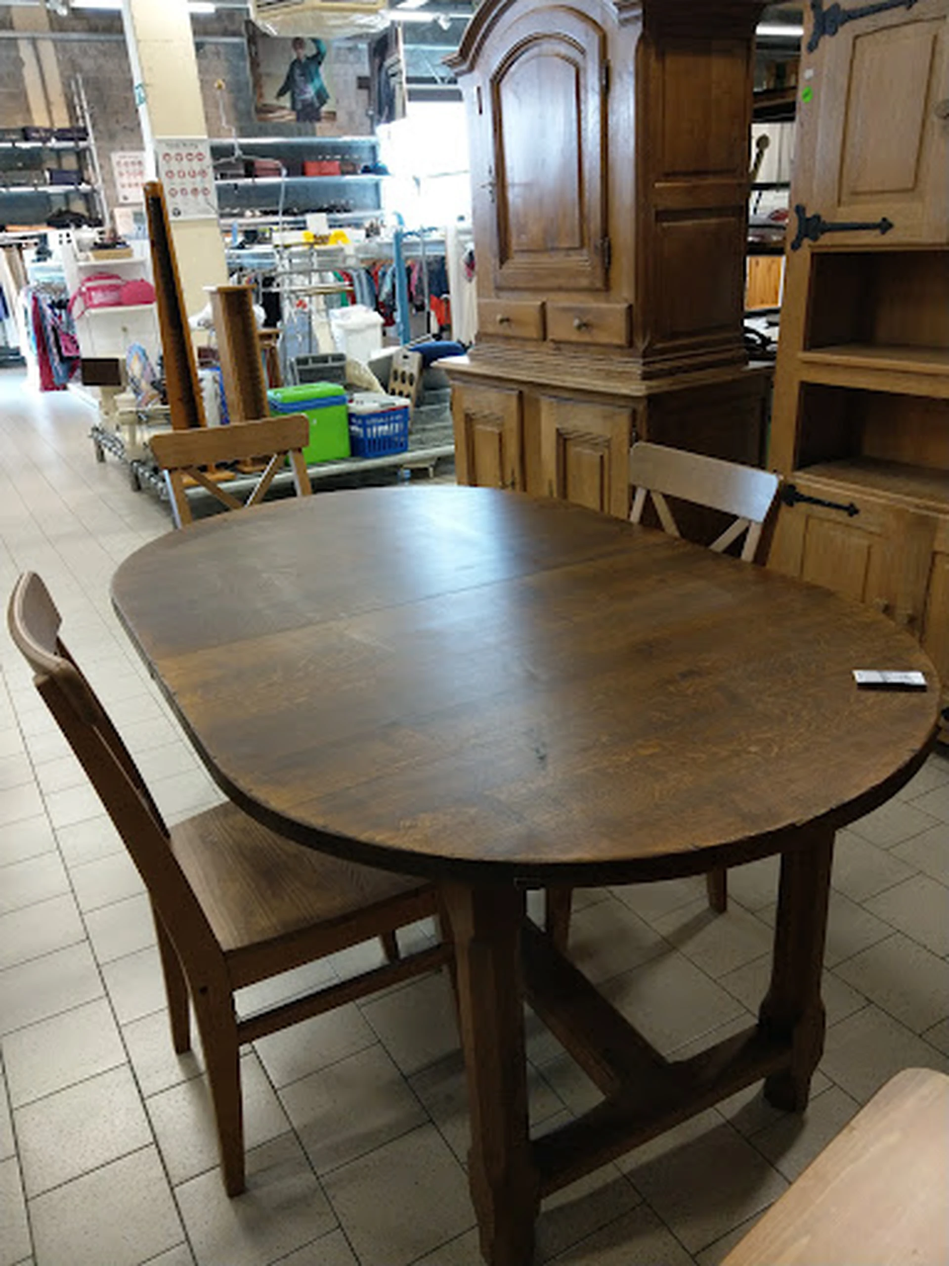 Ronde houten eettafel met uitschuifblad en bruine stoelen in kringloopwinkel