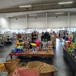 Winkelvloer van kringloopwinkel met speelgoed, meubels en huishoudartikelen uitgestald op tafels en stellingen