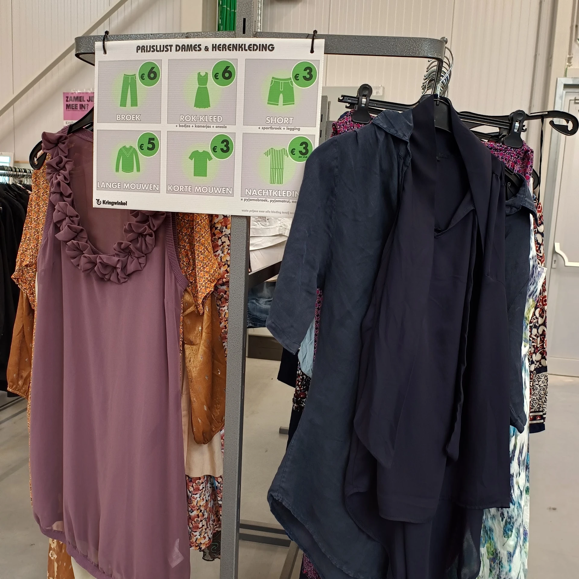 Rekken met tweedehands kleding in diverse kleuren en prints