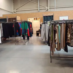 Rekken met tweedehands kleding in verschillende kleuren en stijlen in een kringloopwinkel