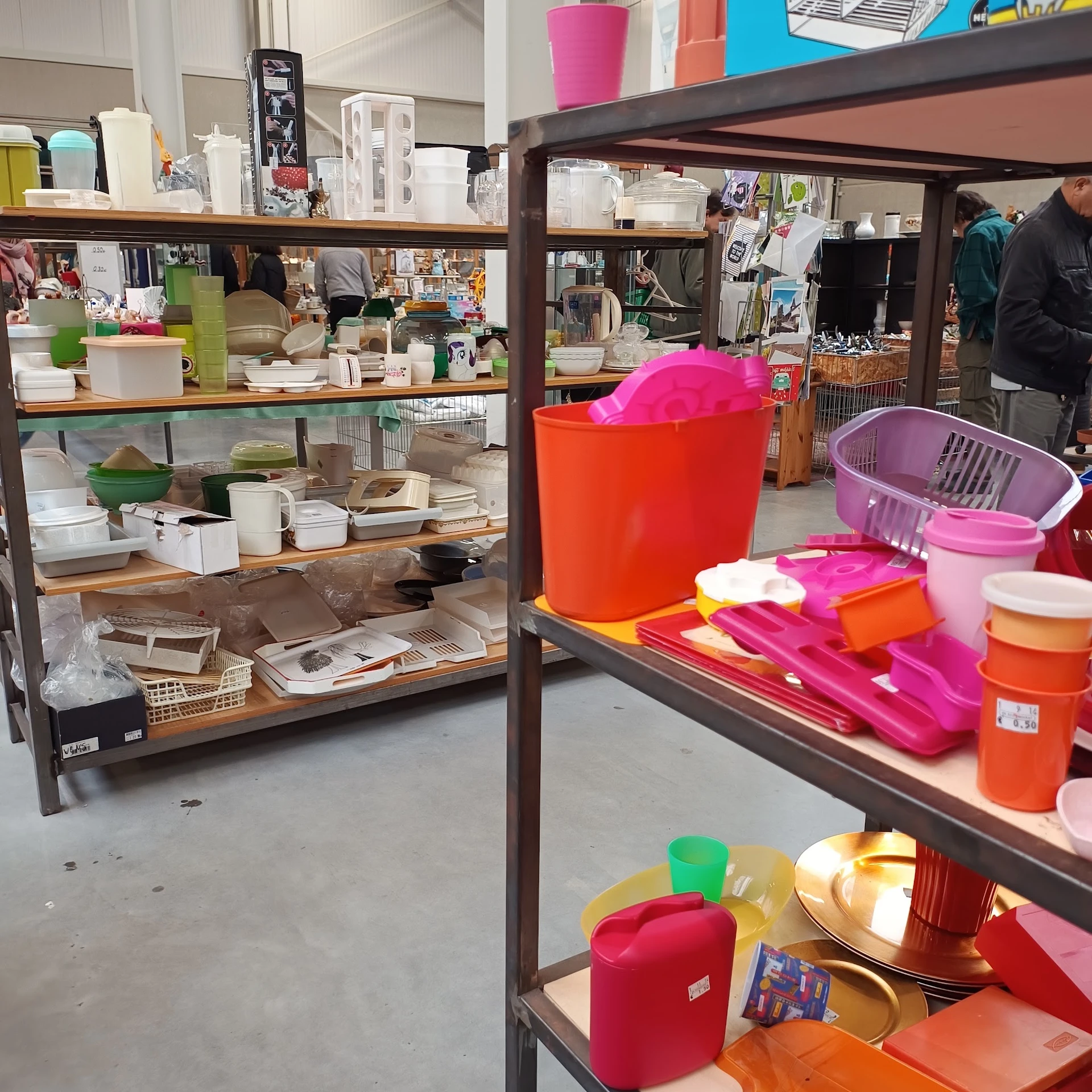 Stellingen en toonbanken met kleurig huishoudelijk aanbod zoals plastic tassen, manden, bakken en servies