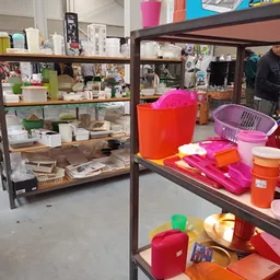 Stellingen en toonbanken met kleurig huishoudelijk aanbod zoals plastic tassen, manden, bakken en servies
