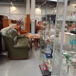 Winkelvloer met groene lederen fauteuil, houten tafeltje en glazen vitrinekasten met diverse items