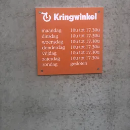 Openingstijden bord van Kringwinkel op muur gemonteerd