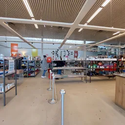 Ruim winkelvloer van een kringloopwinkel met diverse stellingen, rekken en uitgestalde artikelen, helder verlicht
