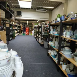 Brede winkelgang met zwart-gouden stellingen vol servies, huishoudartikelen en decoratie-items