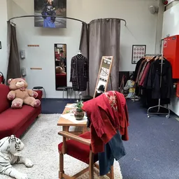 Winkelvloer met kledingrekken, rode bank met knuffels en houten tafel met rode kleding erop
