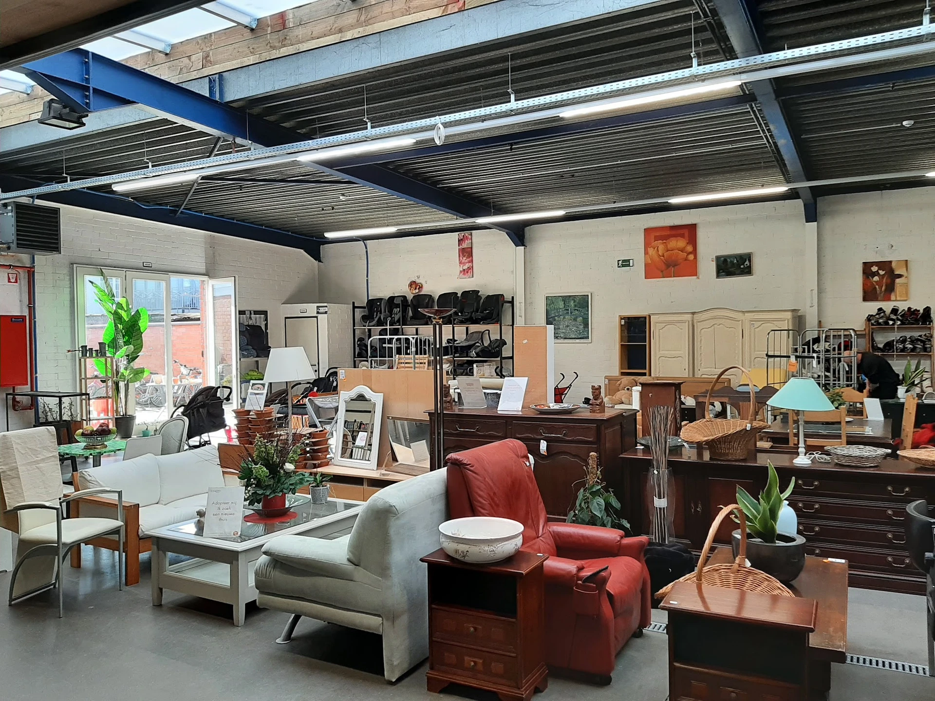 Winkelvloer met meubels, huishoudartikelen en decoratie, onder industrieel plafond met daklichten