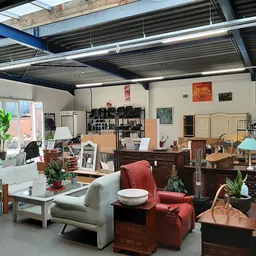 Winkelvloer met meubels, huishoudartikelen en decoratie, onder industrieel plafond met daklichten