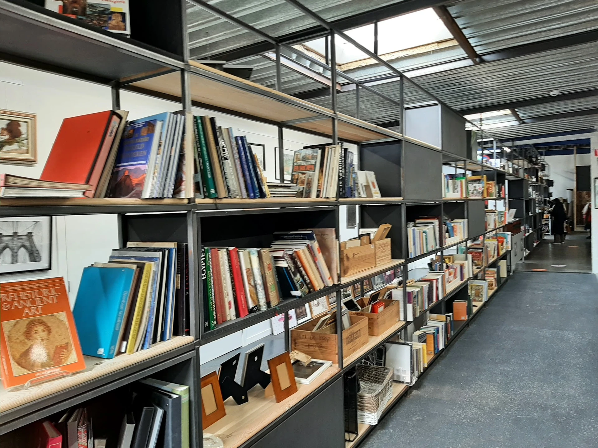 Stellingen vol met boeken en andere artikelen in een kringloopwinkel