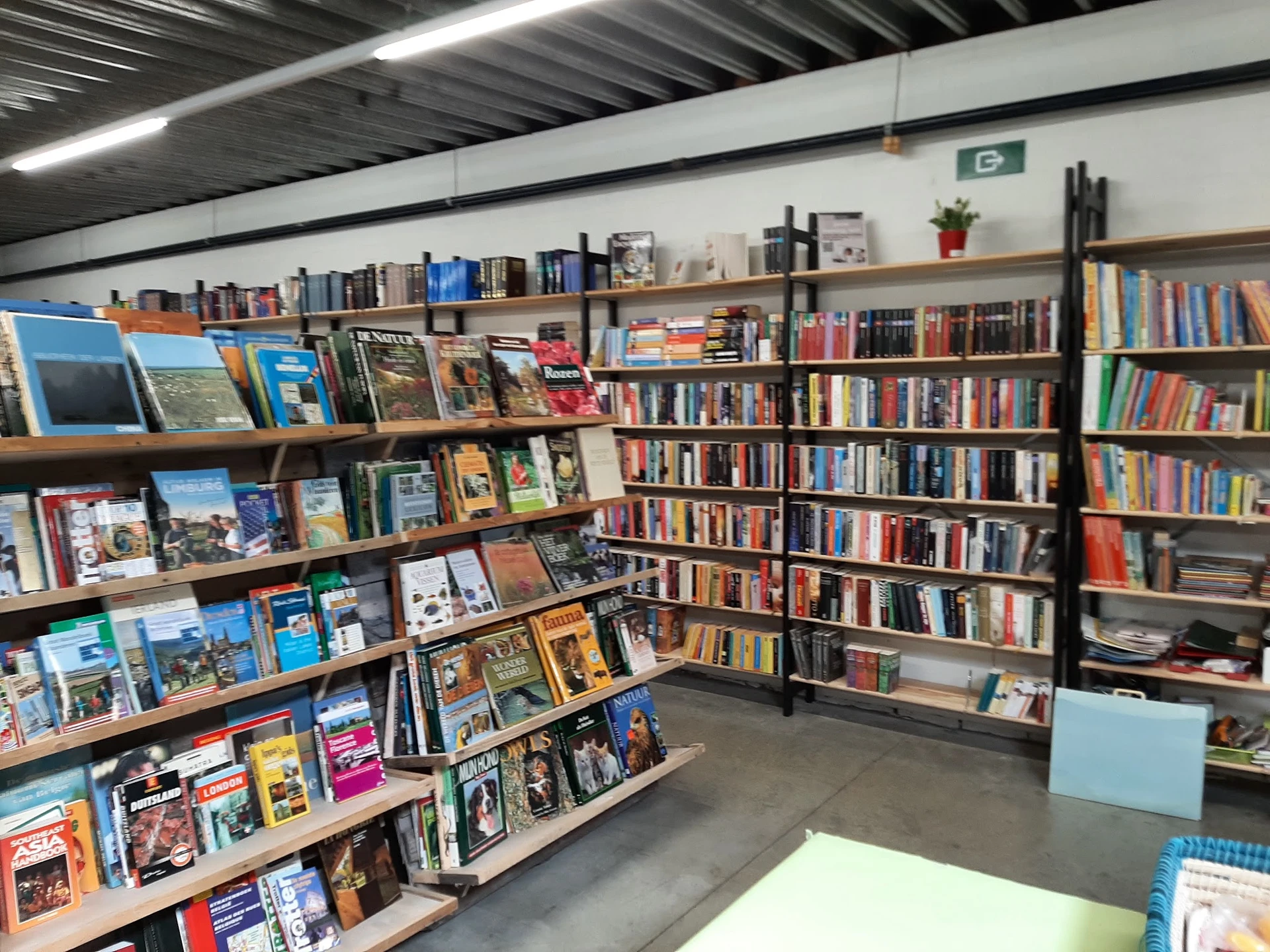 Boekenrekken en boekenstalages in een kringloopwinkel met diverse titels en genres