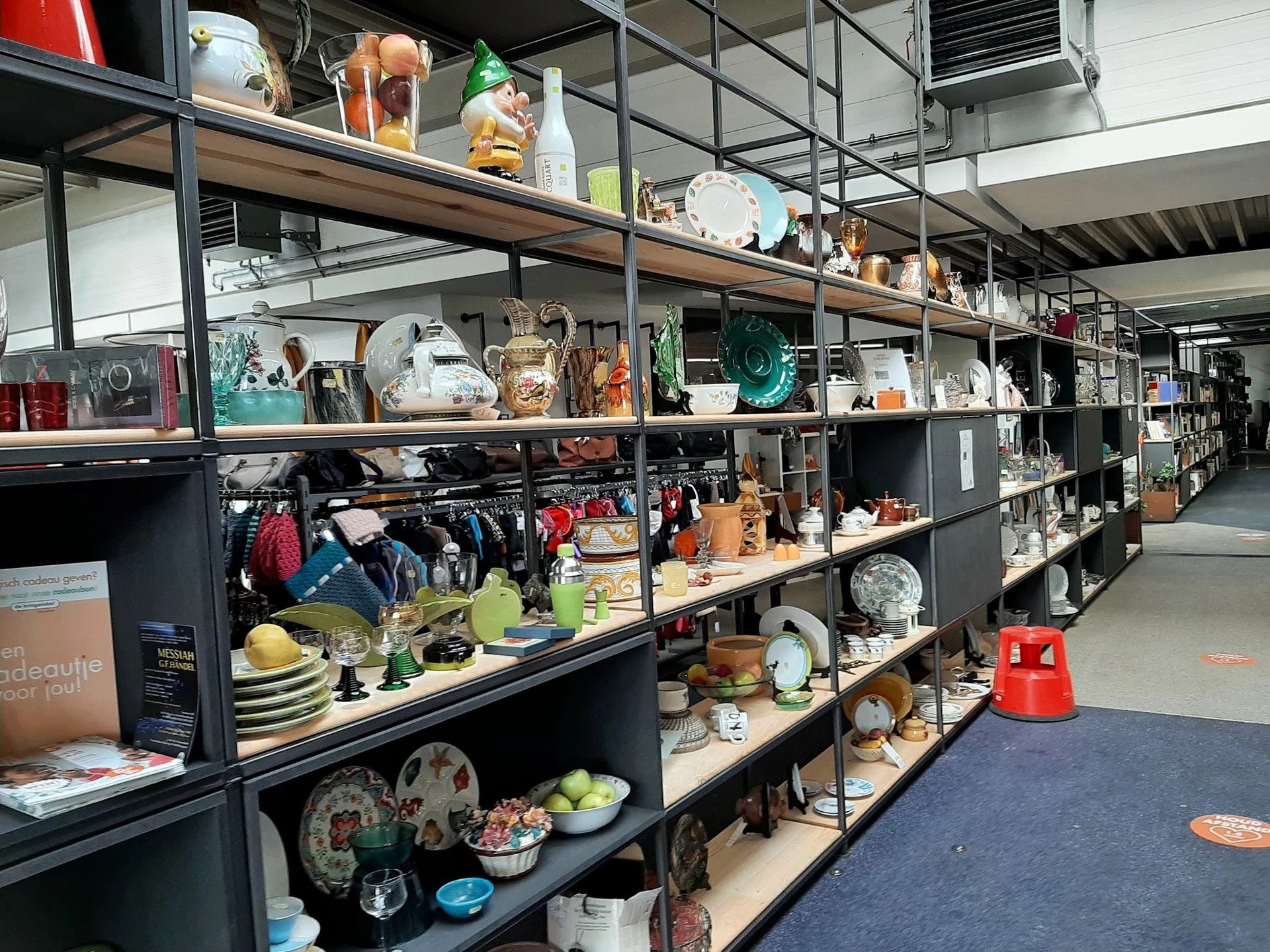 Metalen stellingen met diverse tweedehands huishoudartikelen, servies, decoratie en gebruiksvoorwerpen