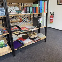 Houten stellingen met diverse spullen: glazen, boeken, laptops, servies en andere huishoudartikelen