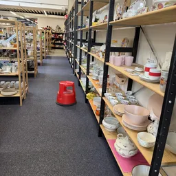 Stellingen met serviesgoed, kopjes, borden en huishoudartikelen in een kringloopwinkel