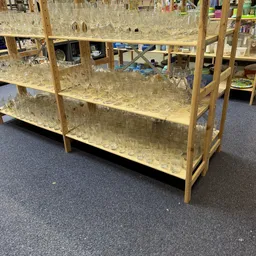 Houten stellingkast gevuld met glazen glazen op een grijze winkelwloer