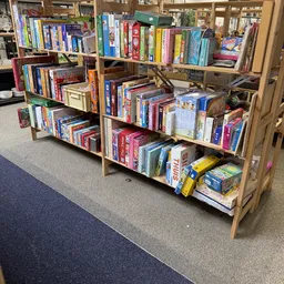 Houten stellingen gevuld met diverse bordspellen, dvd's en media-producten in een kringloopwinkel