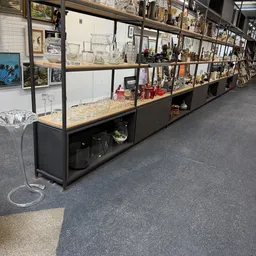 Lange vitrinekast met glazen deuren vol tweedehands huishoudartikelen, glazen, vazen en decoratieve items