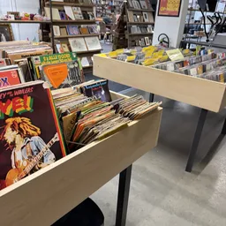 Beige stellingen met vinyl records en cd's uitgestald in een kringloopwinkel
