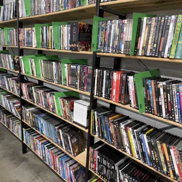 Meerdere rekken met uitgestalde dvd's en blu-rays, netjes georganiseerd op groene en zwarte stellingen