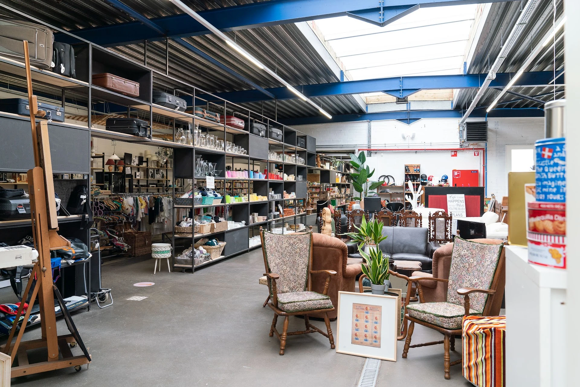 Winkelvloer met meubels, stellingen met diverse artikelen en decoratieve planten in een kringloopwinkel