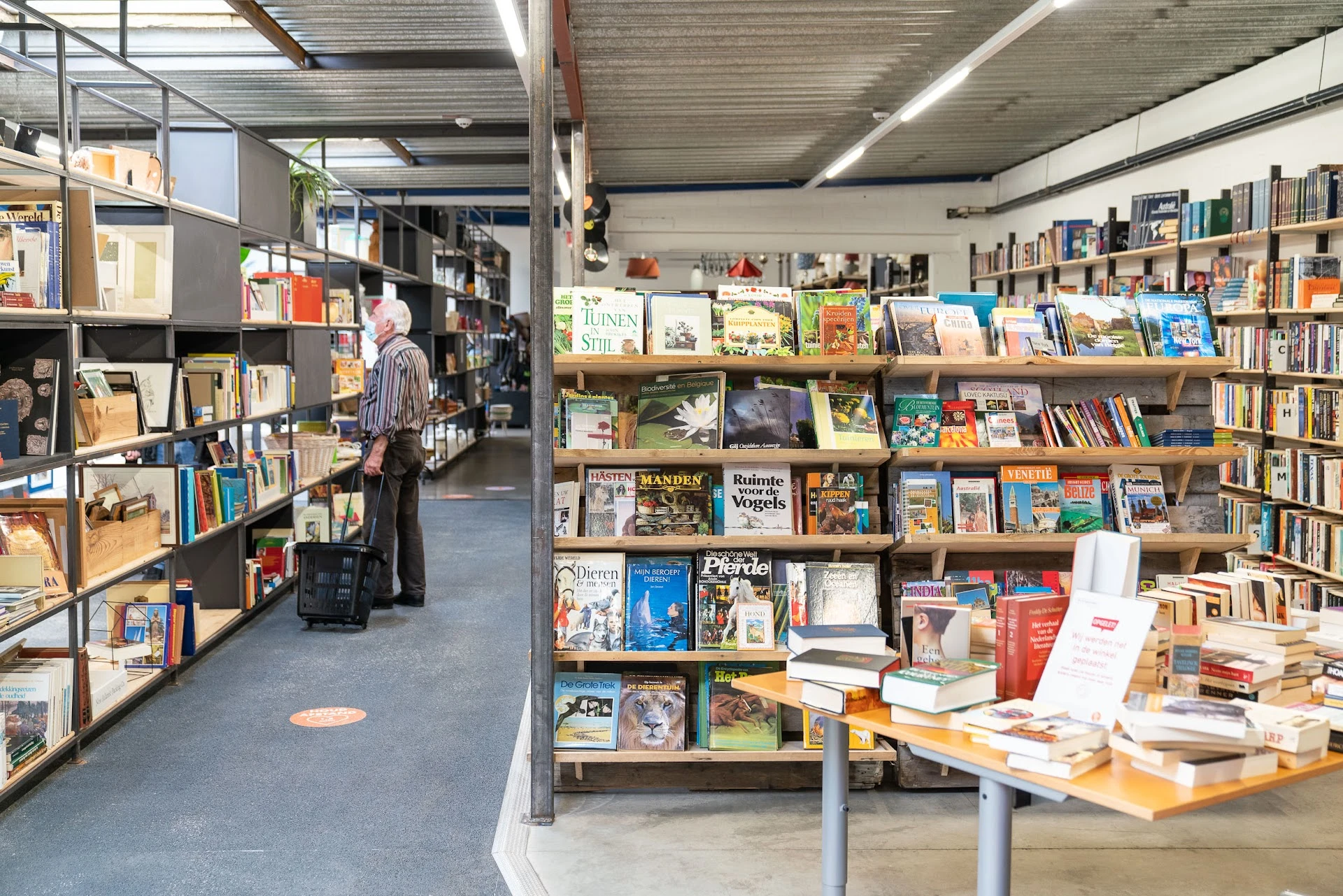 Boekenrekken met tweedehands boeken in een kringloopwinkel, klant aan het bladeren