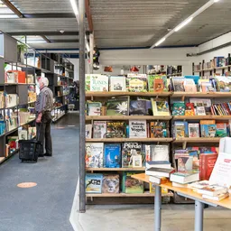 Boekenrekken met tweedehands boeken in een kringloopwinkel, klant aan het bladeren