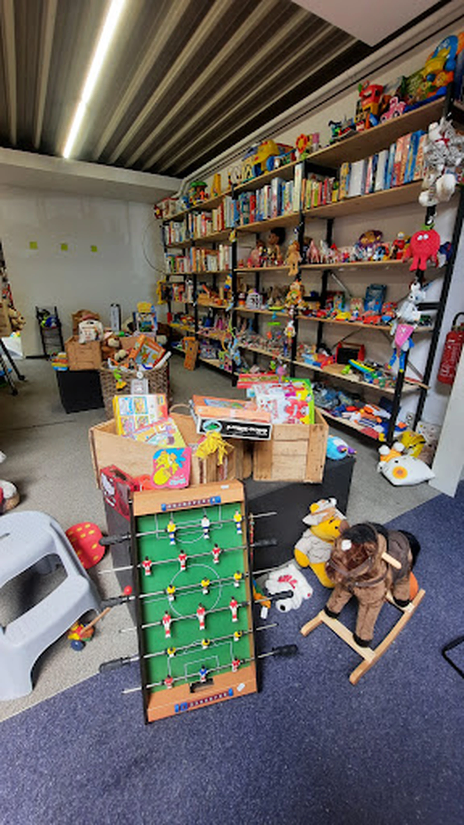 Winkelinterieur met speelgoed, poppen, voetbaltafel en andere spullen op houten meubels en stellingen