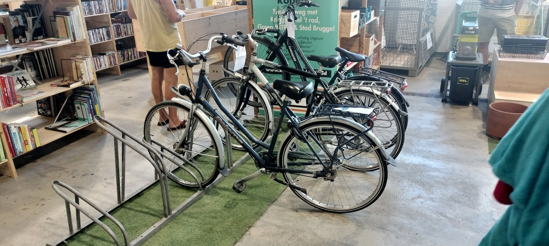Verschillende tweedehands fietsen uitgestald in de winkel, waaronder zwarte en groene modellen