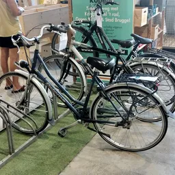 Verschillende tweedehands fietsen uitgestald in de winkel, waaronder zwarte en groene modellen