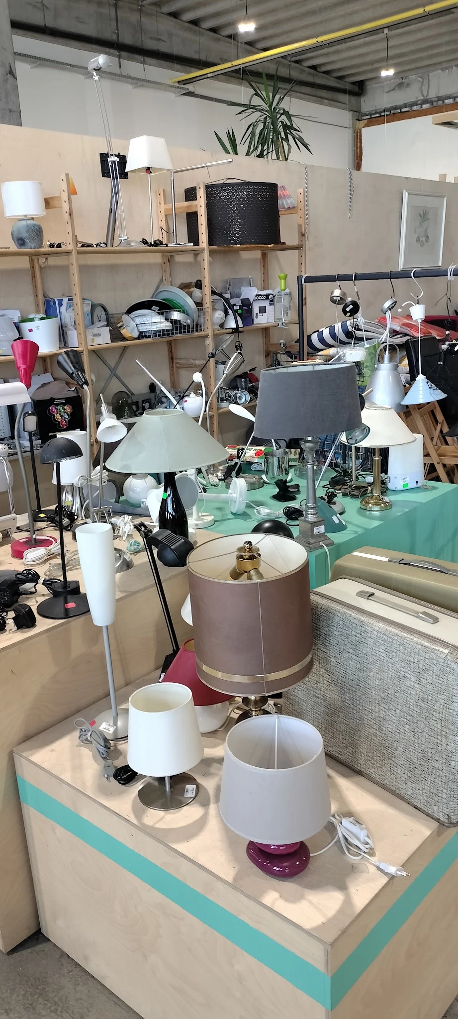 Werkruimte met groene tafel vol lampen, verlichting en diverse huishoudelijke artikelen