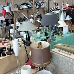 Werkruimte met groene tafel vol lampen, verlichting en diverse huishoudelijke artikelen