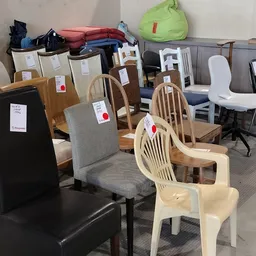 Verschillende houten en kunststof stoelen met prijskaartjes in een kringloopwinkel