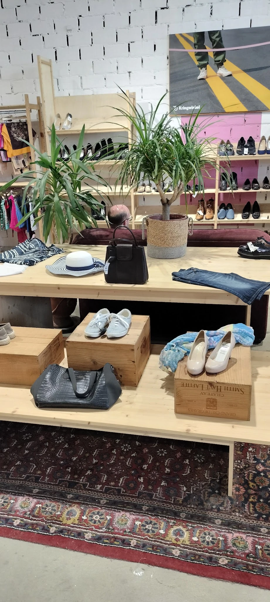 Uitstalling van tweedehands schoenen, tassen en kledingaccessoires op houten blokken en toonbank