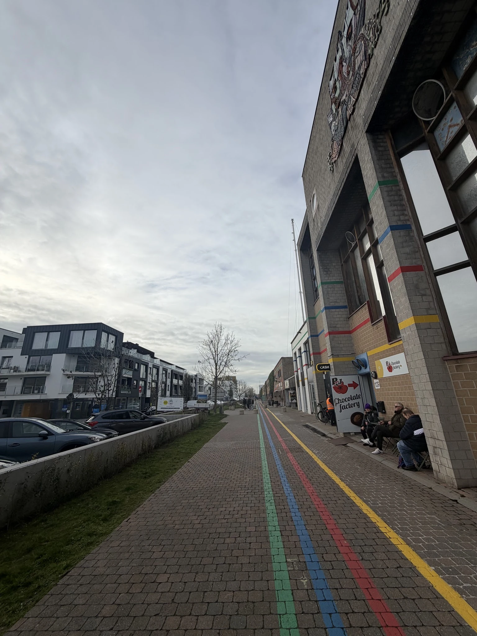 Straatgevel van kringloopwinkel aan Vismijnstraat met grote ramen en gekleurde strepen op baksteenmuur