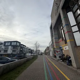 Straatgevel van kringloopwinkel aan Vismijnstraat met grote ramen en gekleurde strepen op baksteenmuur