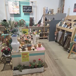 Overzicht van de winkelvloer met uitgestalde vazen, bloemen, decoraties en kunstwerken op stellingen