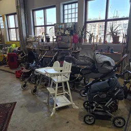 Verschillende kinderwagens en buggy's uitgestald in een winkelruimte met grote ramen