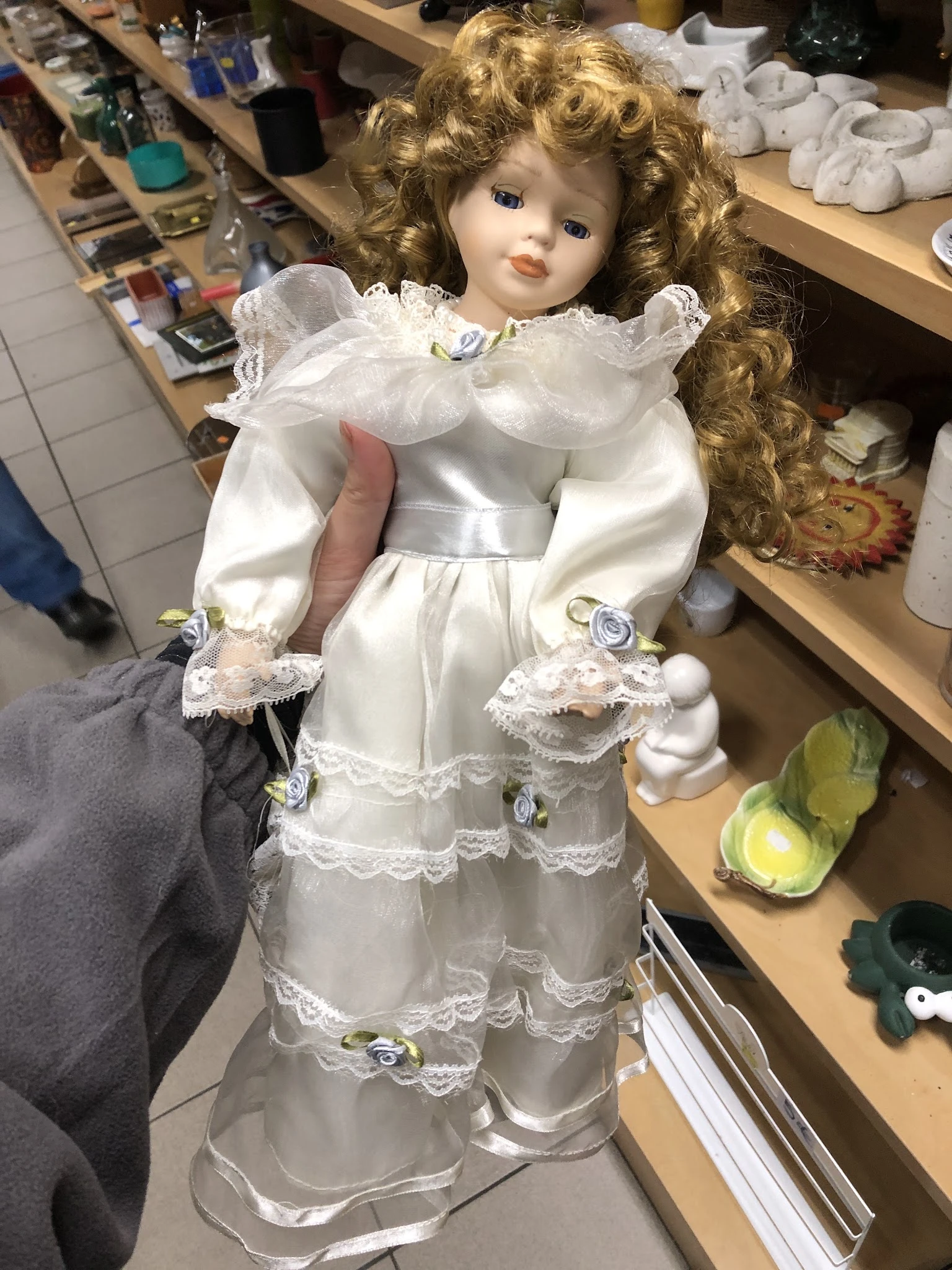 Witte porseleinen pop in vintage jurk met pofmouwen en kantdetails, dicht gezien