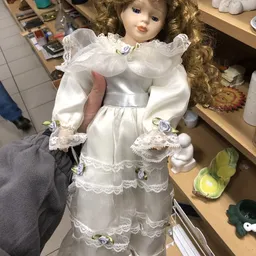 Witte porseleinen pop in vintage jurk met pofmouwen en kantdetails, dicht gezien