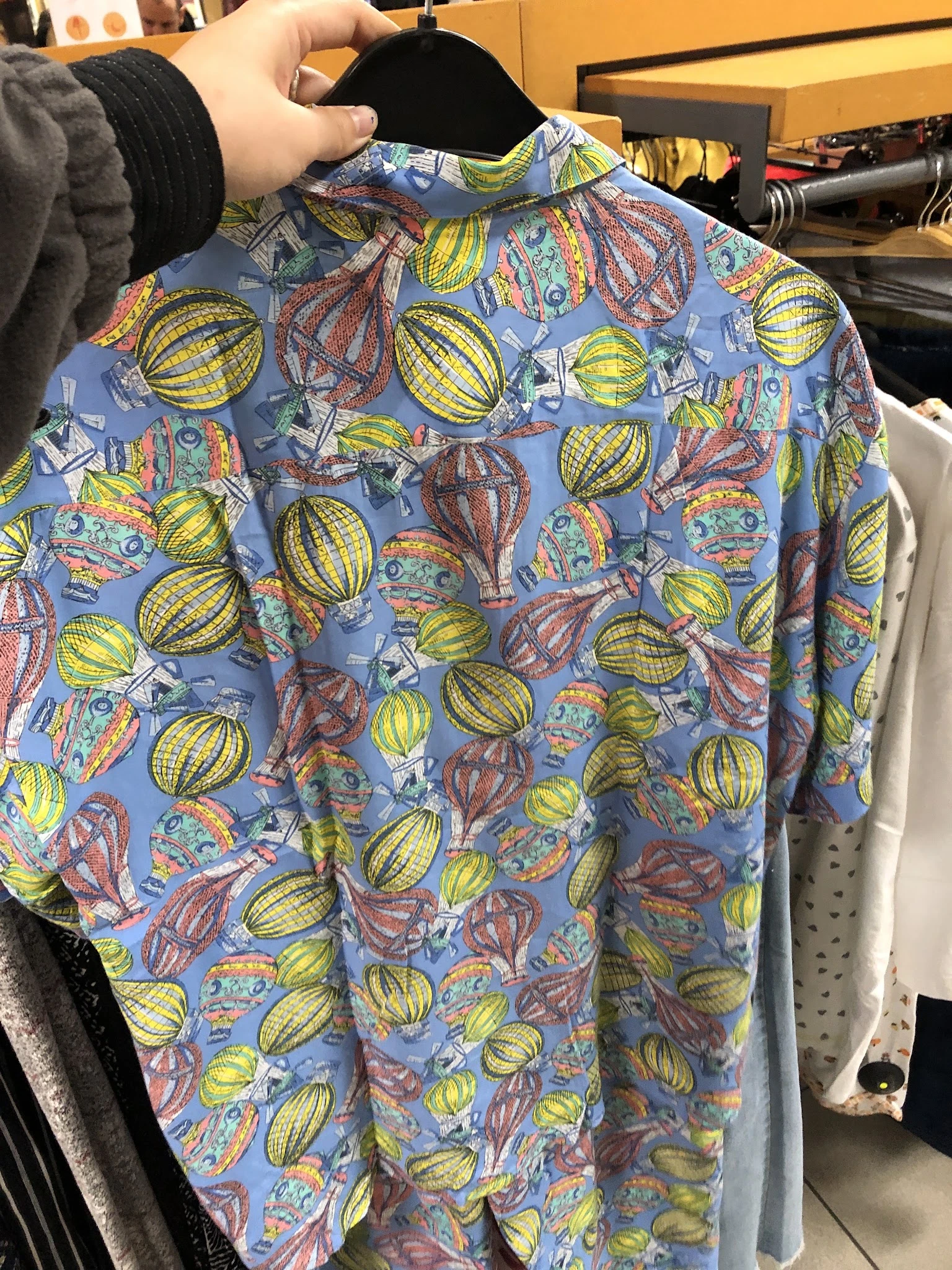 Close-up van een blauw shirt met kleurrijke print van luchtballonnen en vliegtuigen