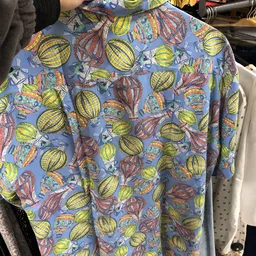 Close-up van een blauw shirt met kleurrijke print van luchtballonnen en vliegtuigen