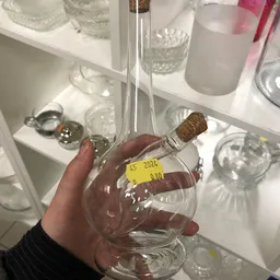 Glazen flesje met kurk en geel prijskaartje '45 2024 0.80' gehouden in hand