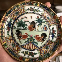 Decoratief bord met Aziatisch motief: twee hanen rond bloemen en geometrische rand.