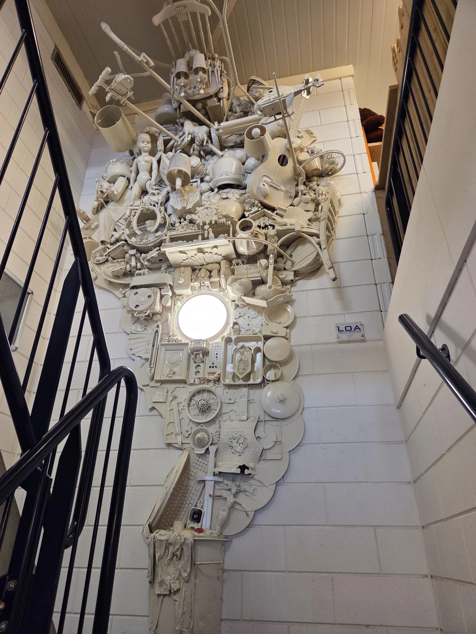 Groot wit kunstwerk gemaakt van plastic huishoudelijke artikelen, opgehangen aan plafond